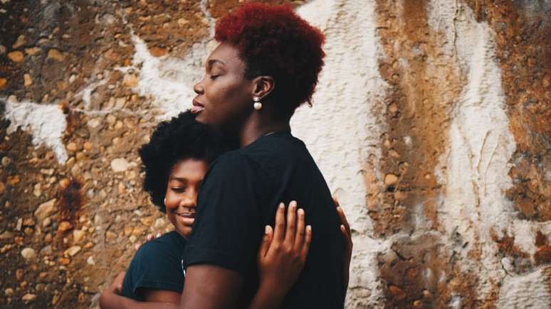 Imagem mostra mulher negra abraçada com a filha.