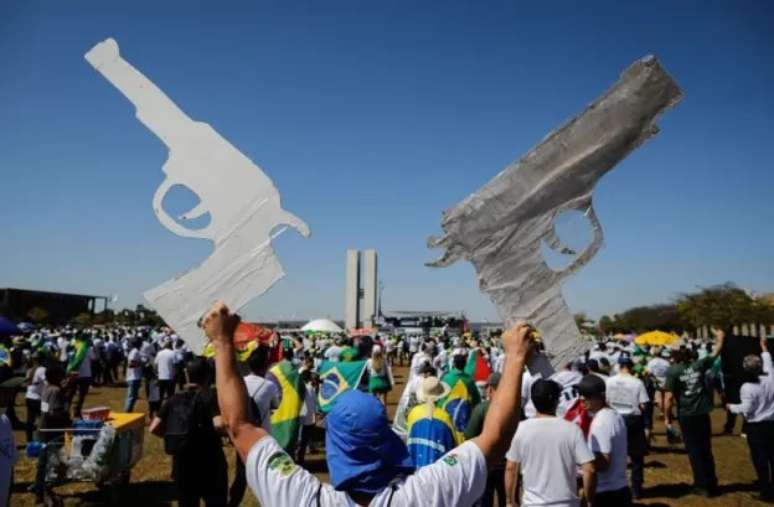 Homem com armas de papelão em comício