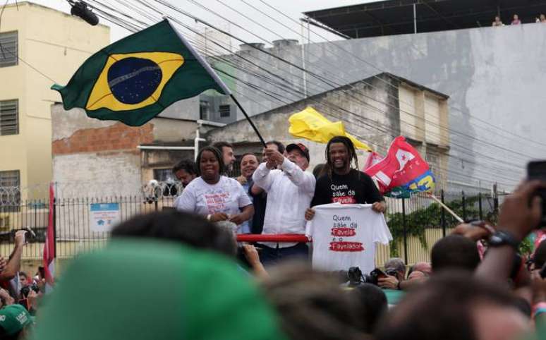 No Alemão, Lula pediu votos de nordestinos contra Bolsonaro vestindo branco e levando a bandeira do Brasil.