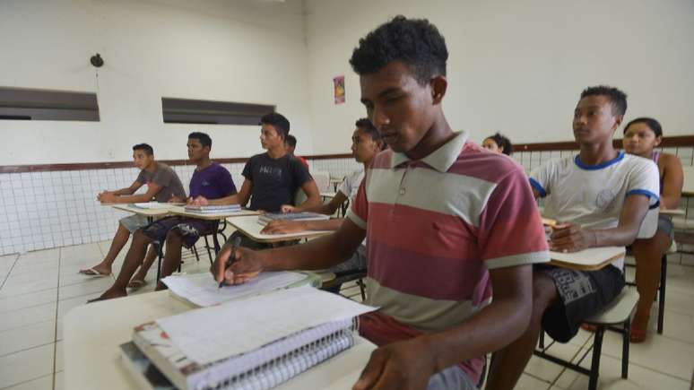 Estudantes pretos estão sentados em cadeiras escolares para retratar a Lei de Cotas