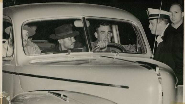 A captura de Pereira Lima: o fugitivo est&aacute; no centro da viatura, entre um motorista e o delegado Nicolau M&aacute;rio Centola