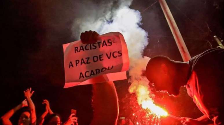 Imagem mostra cartaz com a frase "racistas, a paz de vocês acabou" erguido durante ato do movimento