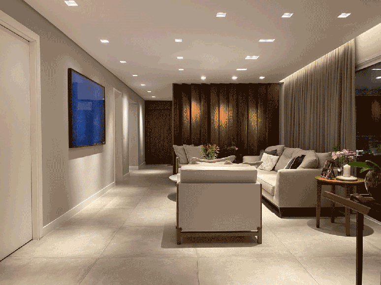 Conjunto de ripas pivotantes &lsquo;dividem&rsquo; a sala de TV e de estar: sua fun&ccedil;&atilde;o &eacute; abrir e fechar dependendo da necessidade do propriet&aacute;rio. Uma solu&ccedil;&atilde;o inteligente para quem n&atilde;o quer integrar ou segregar completamente um ambiente do outro | Projeto Bruno Moraes Arquitetura.