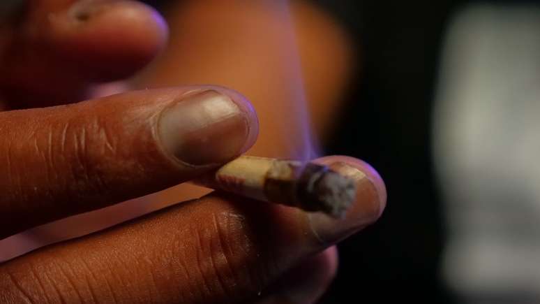 Imagem mostra a mão de uma pessoa negra com um cigarro de maconha.