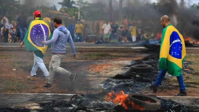 Imagem mostra bolsonaristas queimando pneus em protesto em que contestam o resultado das eleições e atacam a democracia.