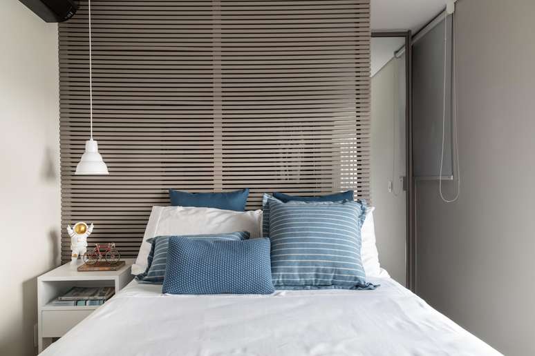 ​No quarto de solteiro, Marina Carvalho visualizou boa solu&ccedil;&atilde;o para separar o ambiente do closet: criou uma cabeceira de cama ripada que divide os dois espa&ccedil;os de um jeito leve e que harmoniza com o d&eacute;cor do dormit&oacute;rio.