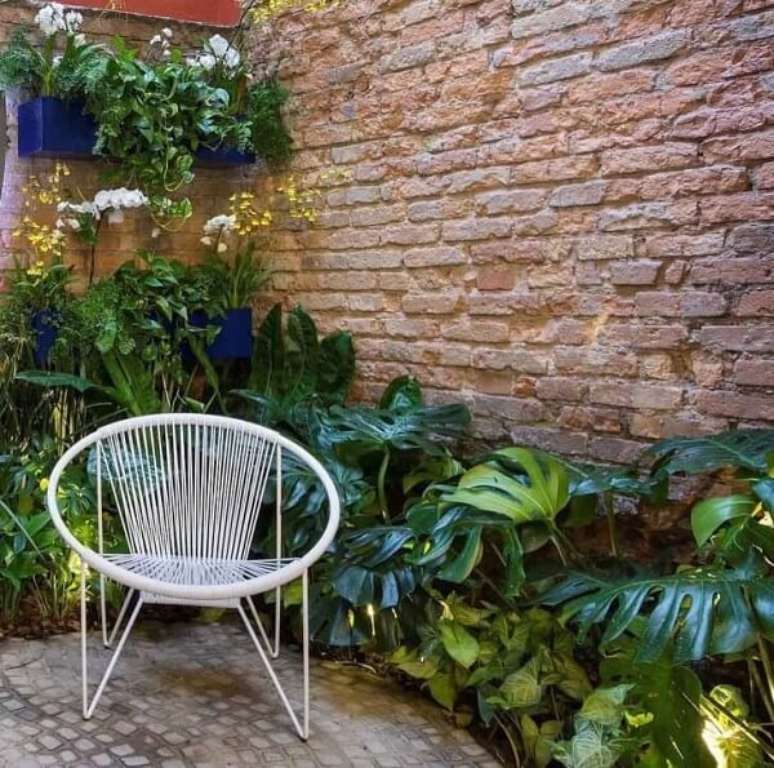 16. Apartamento garden decorado com folhagens e parede de tijolinho aparente. Fonte &ndash; Bia Abreu