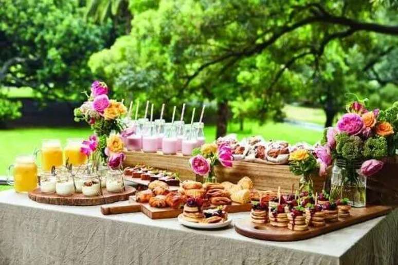 21- A decora&ccedil;&atilde;o de ch&aacute; de casa nova ao ar livre tem tabuas de carne usadas como bandejas. Fonte: Guia Noiva Online