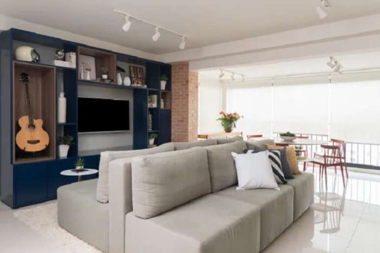 34. Sala com painel azul e sof&aacute;-ilha cinza. Fonte &ndash; Manu Oristanio