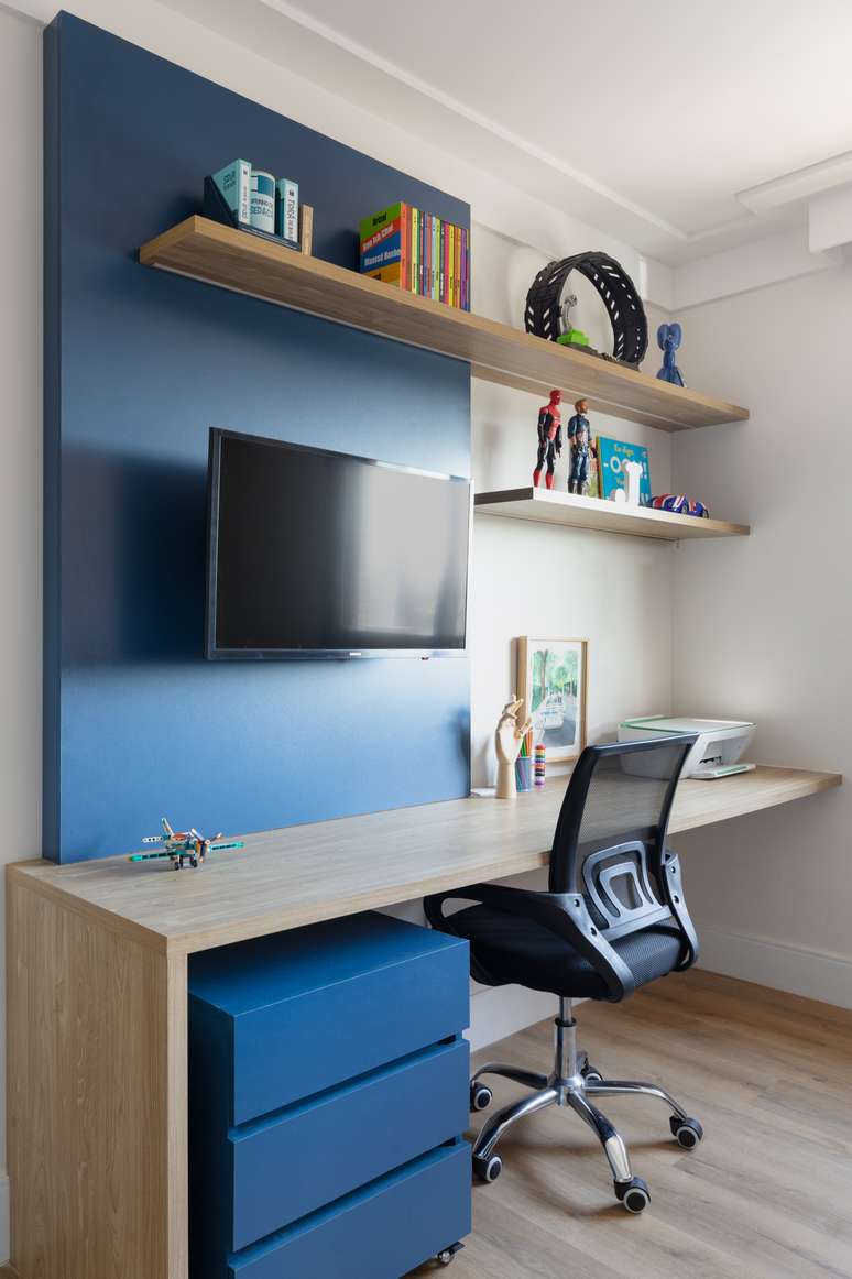 Painel azulado em perfeito alinhamento com gaveteiro de tom similar deu um novo ar ao home office no dormitório. Como a cor incentiva a criatividade e calma, é uma escolha certeira para o ambiente de trabalho | Projeto: Korman Arquitetos.