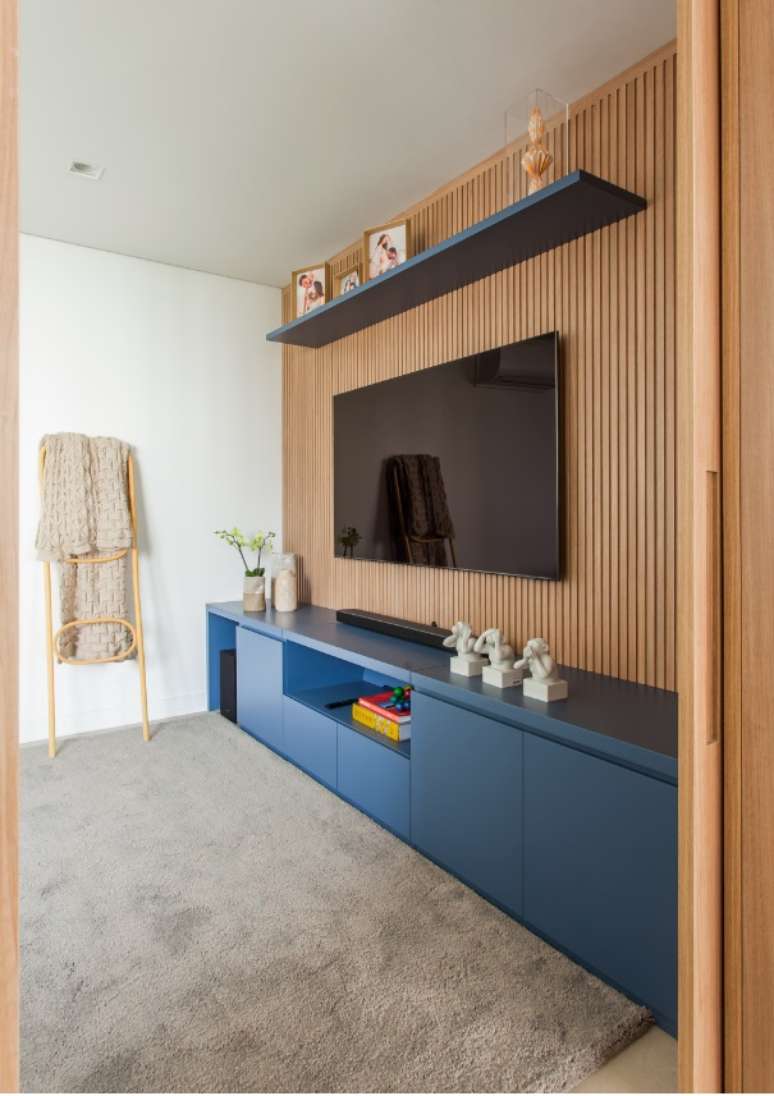O rack azul se complementa com o aconchego do painel ripado da TV instalada no home theater | Projeto: Korman Arquitetos.