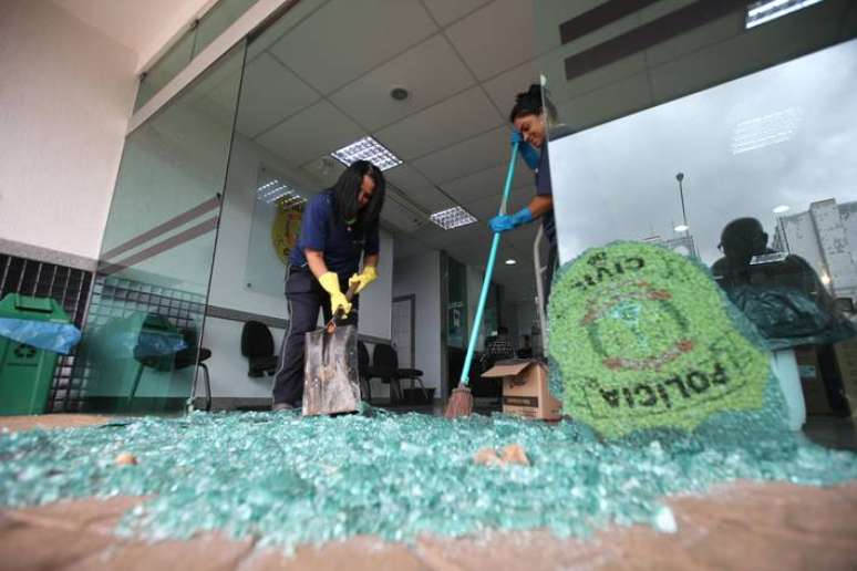 Funcion&aacute;rias da limpeza da 5&ordm; DP do Distrito Federal trabalham na retirada dos cacos de vidro da porta de entrada da delegacia, estilha&ccedil;ada durante protesto ap&oacute;s pris&atilde;o de apoiador de Bolsonaro.