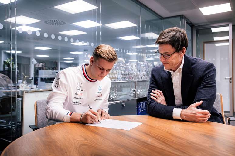 Schumacher assinando o contrato ao lado de Toto Wolff 