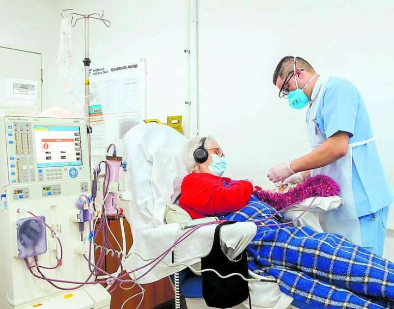 Técnico de enfermagem auxilia paciente durante hemodialise.