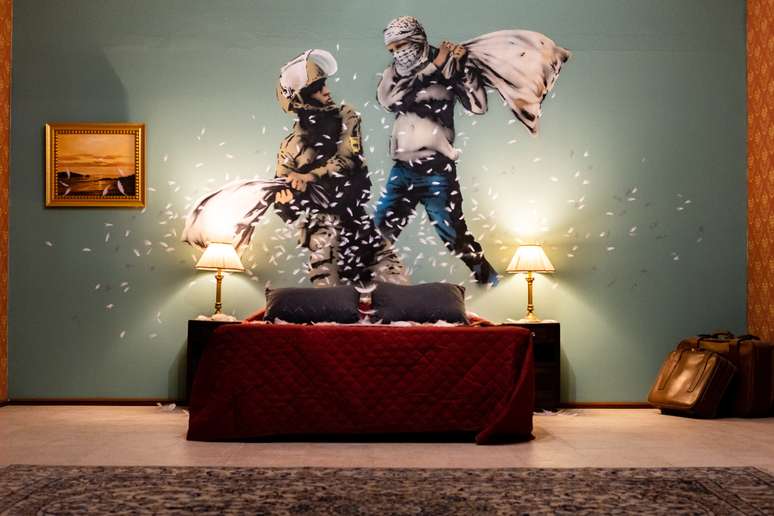 Soldado israelense e militante palestino fazem luta de travesseiro em pintura de Banksy no Walled Off Hotel, na Cisjordânia.