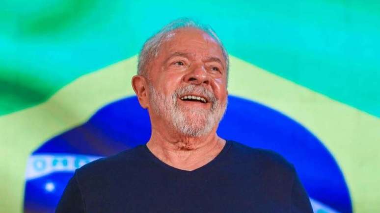 Imagem mostra o presidente eleito Lula com a Bandeira do Brasil ao fundo