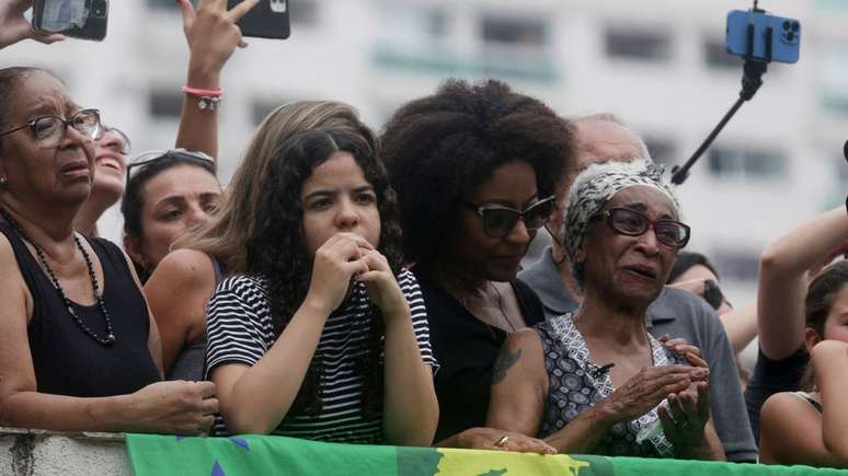 A irmã de pelé, Maria Lúcia Nascimento (à dir., com faixa no cabelo), de 78 anos, assistiu ao cortejo com o caixão ao lado de amigos e familiares