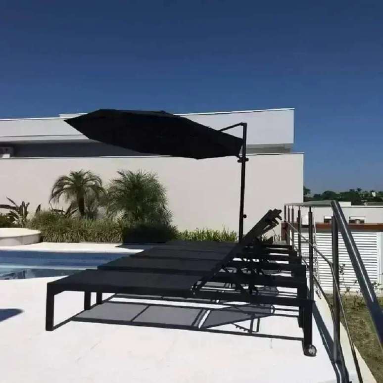 14. &Aacute;rea externa decorada com ombrelone preto e espregui&ccedil;adeira de alum&iacute;nio piscina &ndash; Foto: Requinte Externo