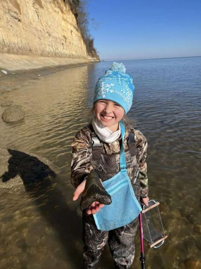 Molly Sampson, de nove anos, segurando o maior dente de megalodon que já encontrou
