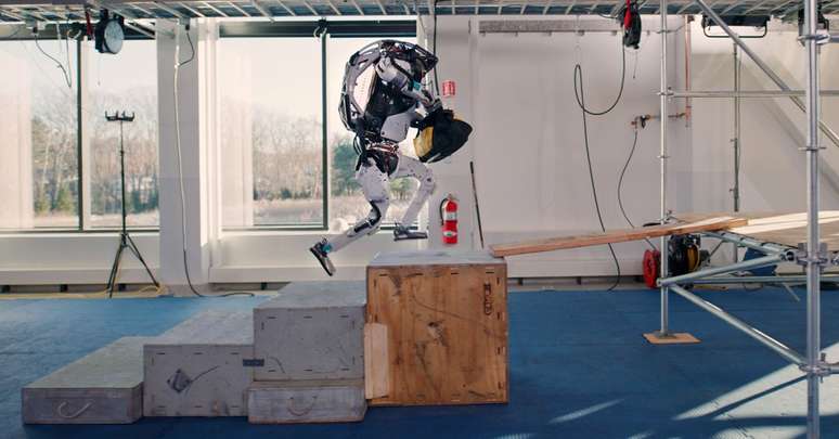 Robô humanoide Atlas subindo escada para entregar ferramentas a uma pessoa 