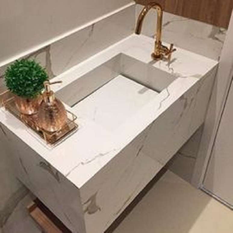 43. Lavabo moderno com pia de m&aacute;rmore esculpido com torneira dourada &ndash; Foto Arkpad