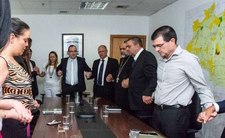 Carla Costa, à esquerda, reza ao lado de diretores da Funai, do presidente Marcelo Xavier, e de Padre Kelmon, na sala da Funai, em outubro de 2022