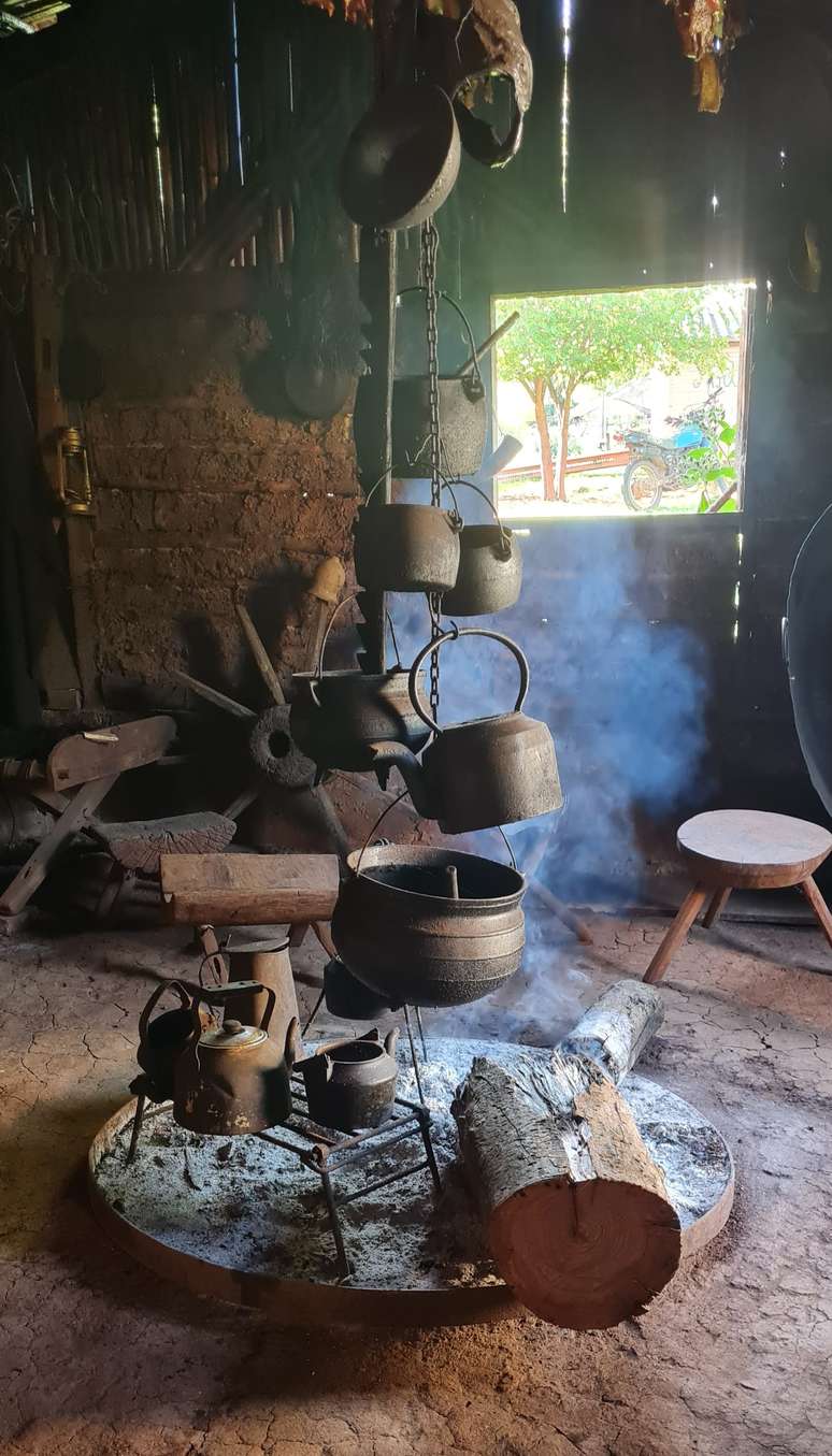 No canto direito do celeiro, uma grande tora chamada de 'borraio' queima ha cinco anos; ao redor dela, salames s&atilde;o defumados.