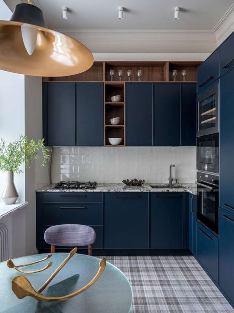 Room with planned joinery, granite countertops, stovetop, chrome faucet, blue chair, and round table.  Source: Viva Decora magazine