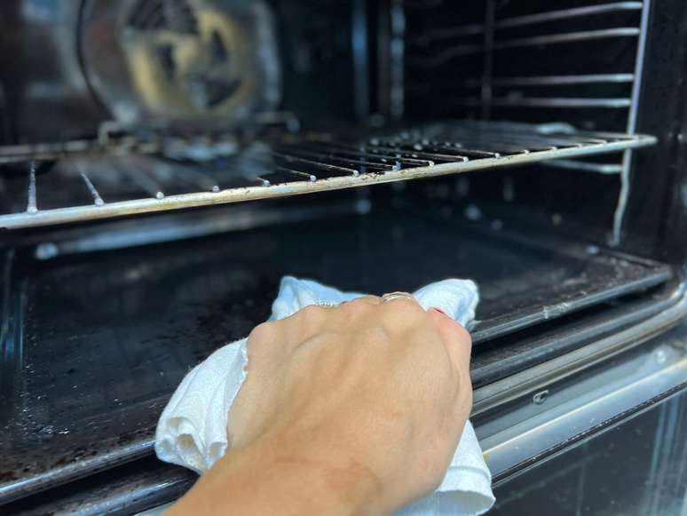 Passando pano úmido com desengordurante no forno quente