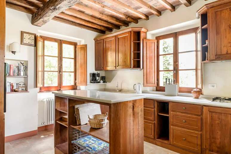 A cozinha segue a decora&ccedil;&atilde;o do restante da vila, com m&oacute;veis de madeira escura.