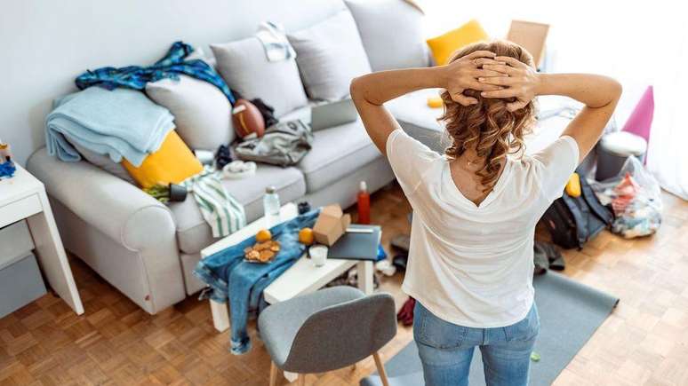 Woman on her back with hands behind head looking at messy house