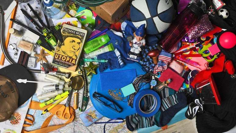 Various objects stacked - cap, book, ball, scissors, pen, glasses, toy, bottle, among others