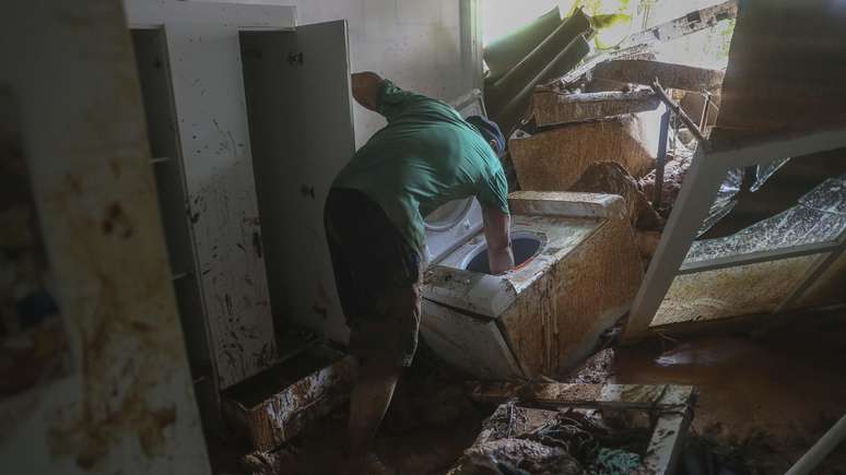 Morador em São Sebastião, no litoral paulista, tenta recuperar objetos levados pela enchente