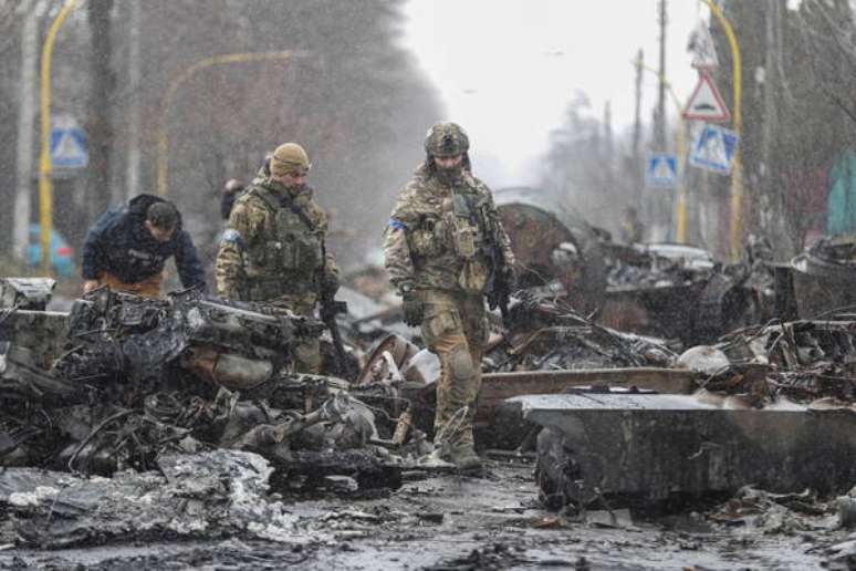 Militares ucranianos inspecionam tanque russo destruído em Bucha, nos arredores de Kiev