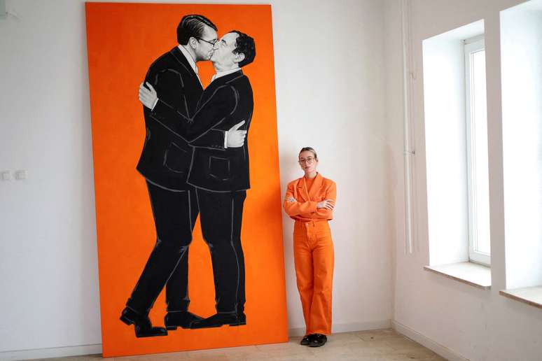Ermira Murati posa ao lado de pintura que mostra o primeiro-ministro de Kosovo, Albin Kurti, e o presidente s&eacute;rvio, Aleksandar Vucic, se beijando