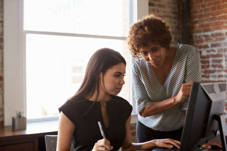 Two women working in front of a computer screen