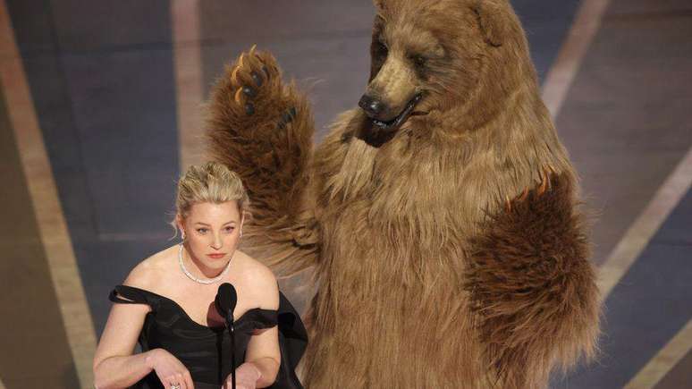 Elizabeth Banks ao lado de um urso no palco, ao apresentar Oscar de efeitos especiais