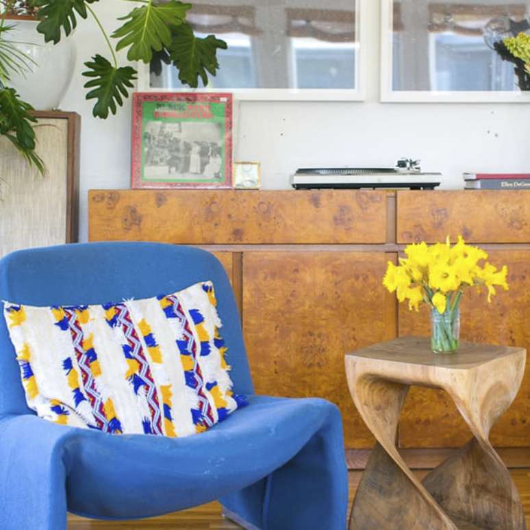 Significado das flores na decora&ccedil;&atilde;o; narcisos amarelos em copo de vidro sobre mesa lateral de madeira