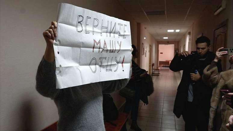 Um apoiador de Alexei Moskalev levanta um cartaz no tribunal local que diz: "Devolva Masha para seu pai!"