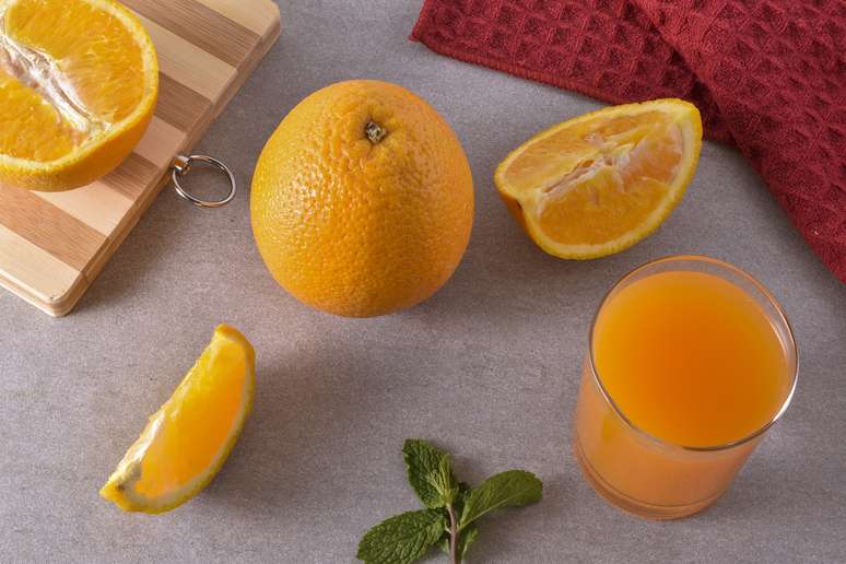 Laranjas e um copo com suco da fruta