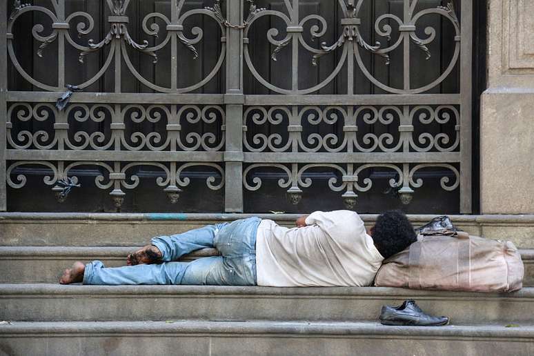 Homem dorme nas escadarias em frente ao Teatro Municipal, no Rio de Janeiro