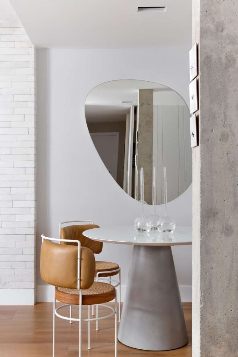 Small dining room with round table and organically shaped mirror.