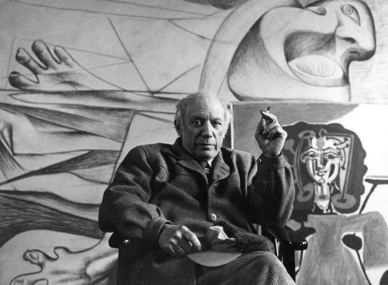 Pablo Picasso em Paris, no ano de 1950, sentado em frente a suas obras.