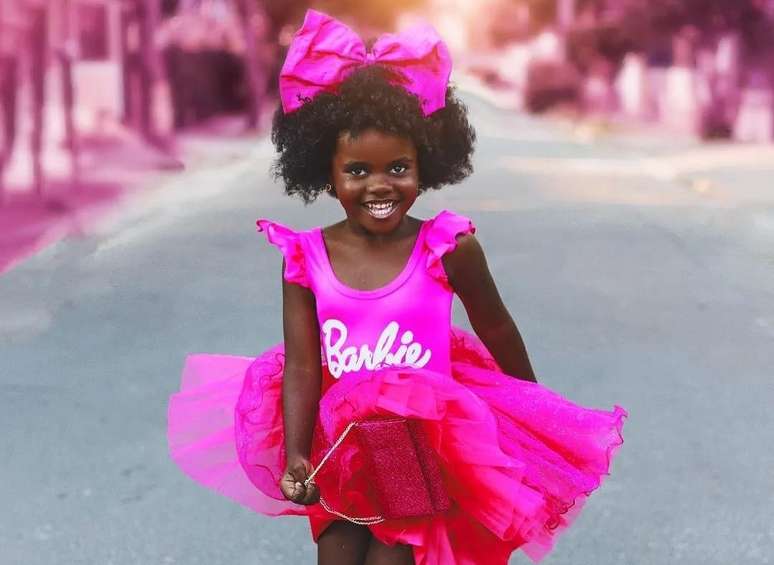 Uma boneca barbie com uma roupa rosa que diz 'menina negra' nela