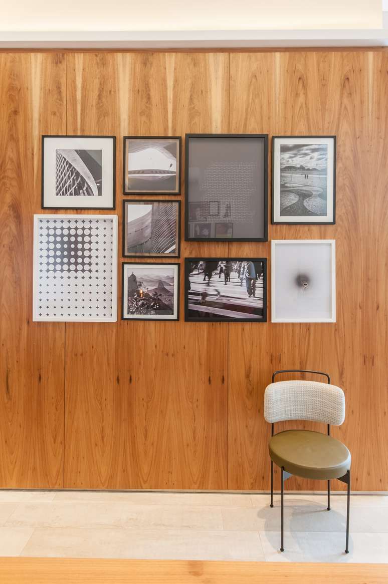 Exemplo de gallery wall minimalista, tanto em visual, como nas gravuras. A est&eacute;tica preta e branca prevaleceu, equilibrando bem o d&eacute;cor com a calorosa parede de madeira. Projeto: Paiva e Passarini - Arquitetura.