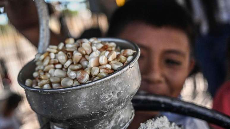 Uma criança indígena Wayuu moe milho para fazer a chicha em sua casa na comunidade Witka, no departamento de La Guajira, na Colômbia