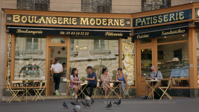 Emily (Lily Collins) entrando na Boulangerie Moderne em cena de Emily em Paris.