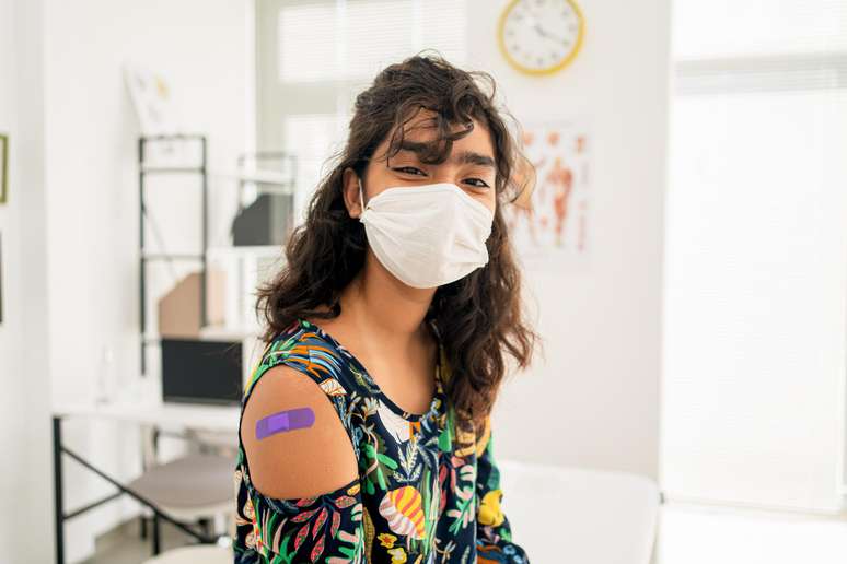 teenager wearing a mask and with a post vaccine bandage on his arm teenager wearing a mask and with a post vaccine bandage on his arm