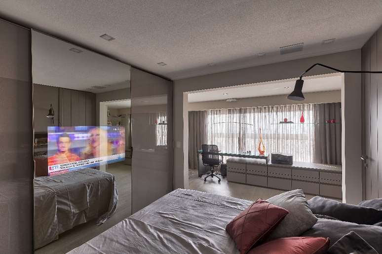 With a view to optimizing space for better circulation, in this bedroom, architect Cristiane Schiavoni installed the TV directly on the mirrored door of the wardrobe, presenting a modern and multifunctional solution for the residents.