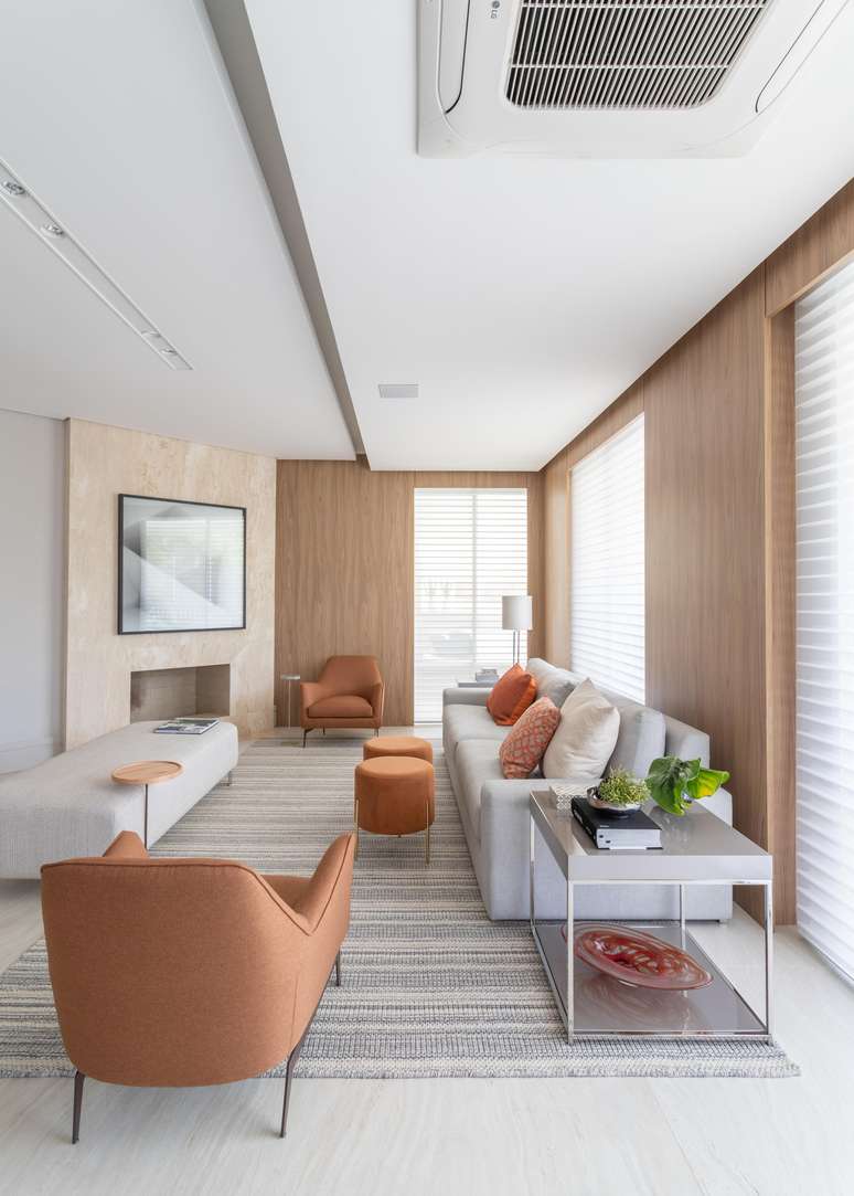 As poltronas, almofadas, pufes e o tapete ganharam coloração em tons terrosos, configurando-se um living charmoso e muito aconchegante! Ademais, a lareira se torna outro ponto de acolhimento e arremata o ambiente de maneira elegante e coesa. Projeto: Patricia Penna Arquitetura & Design.